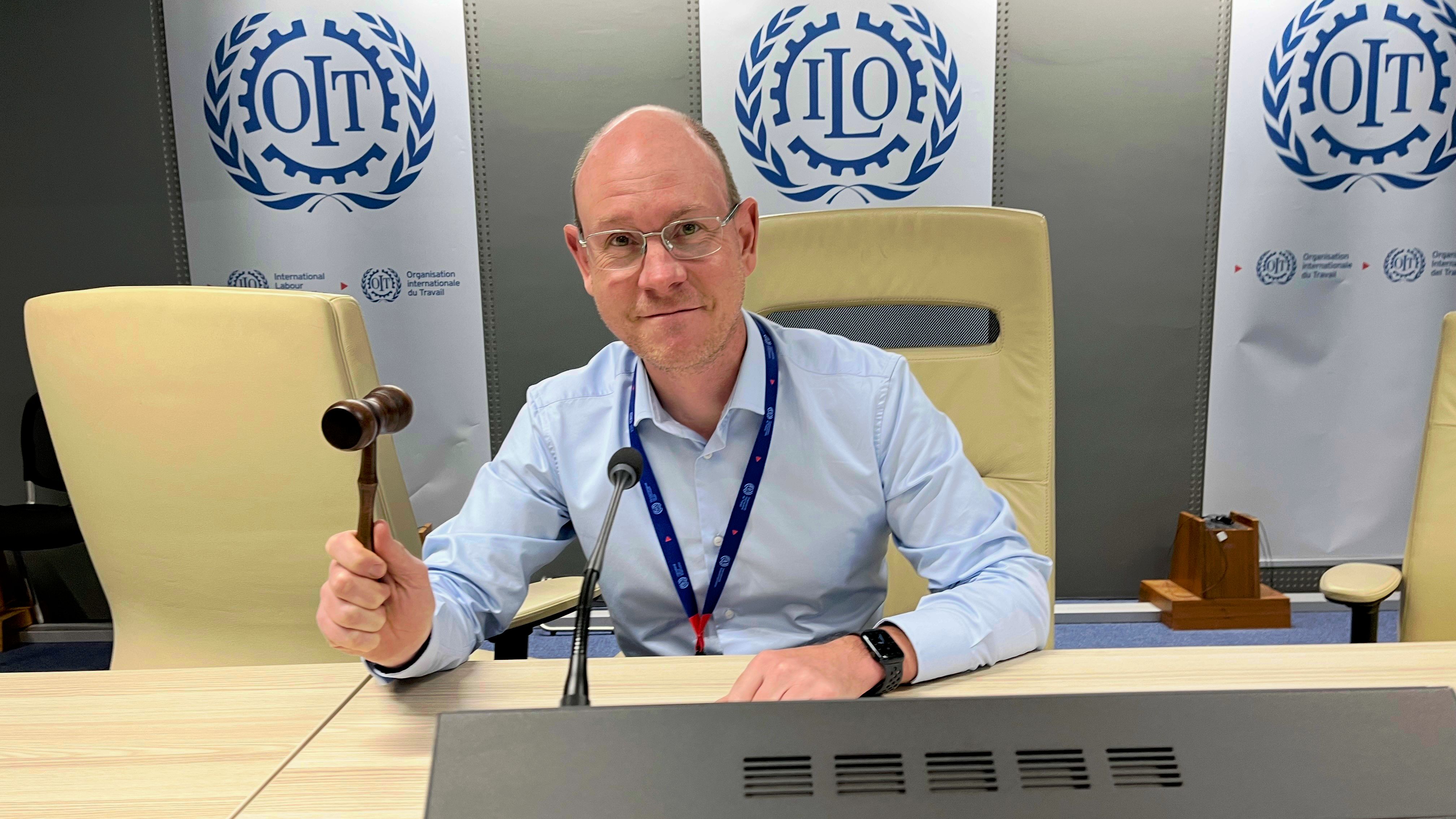 Me holding a gavel in front of an ILO logo banner